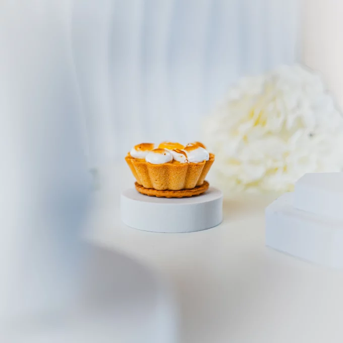 Tartaletka cytrynowa z bezą włoską na białym tle, elegancko zaprezentowana w minimalistycznej aranżacji