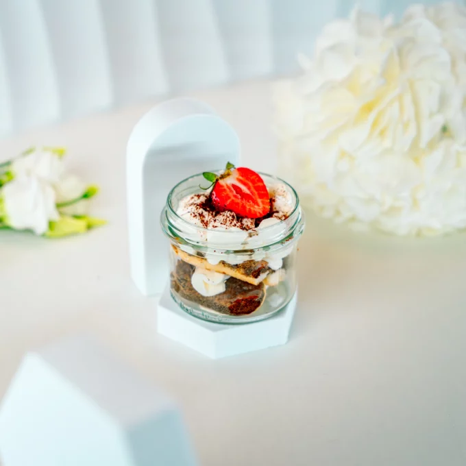 Tiramisu w szklanym słoiczku z biszkoptami, kremem mascarpone i truskawką na wierzchu