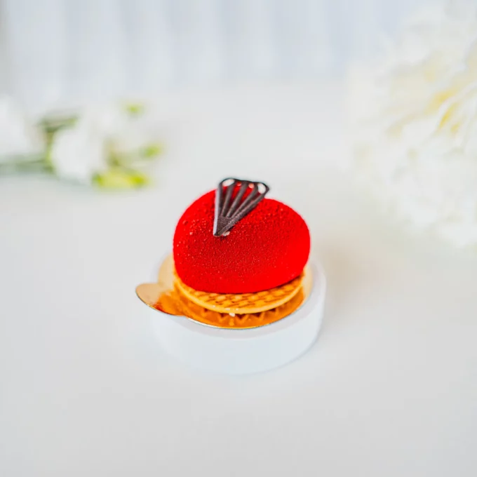 Elegancka monoporcja truskawkowa w czerwonej aksamitnej glazurze z dekoracją z ciemnej czekolady